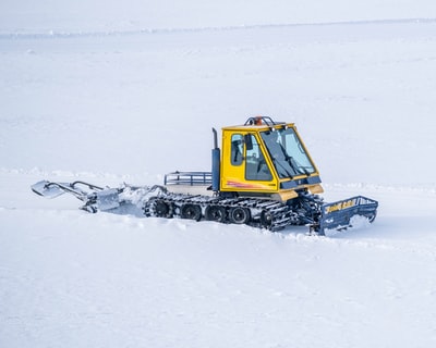 白天，黄色和黑色拖拉机在雪地上行驶